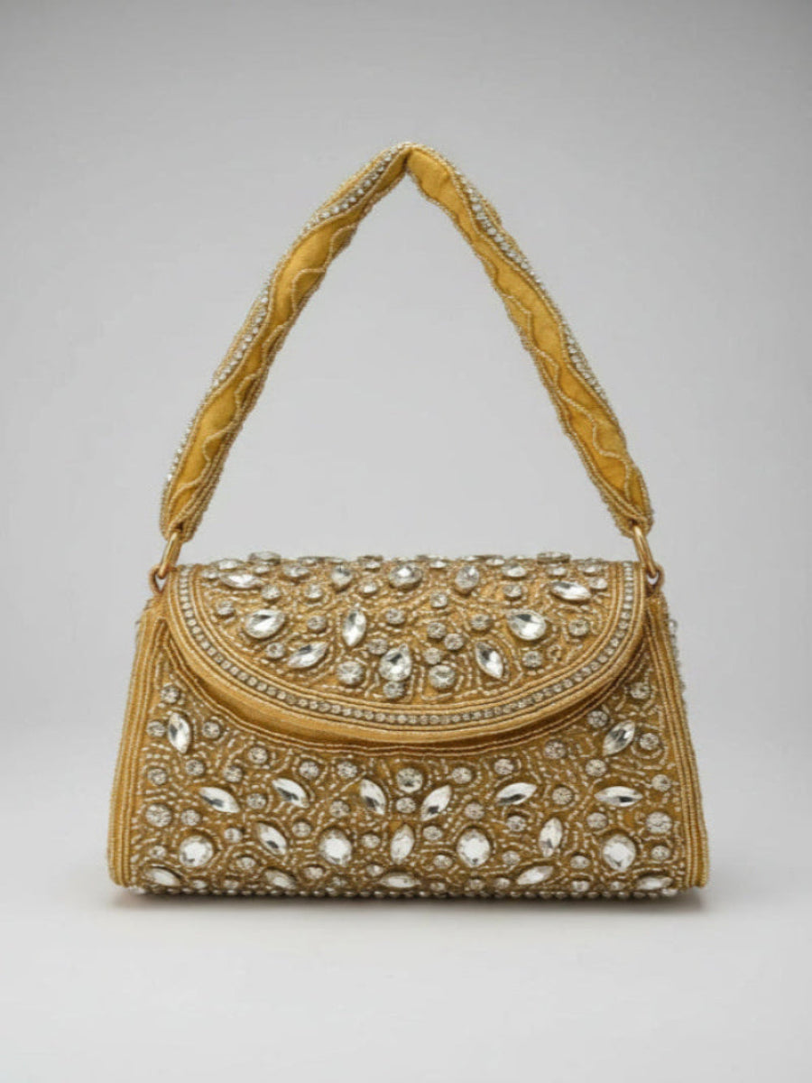 Gold handbag with intricate gemstone detailing on a gray background
