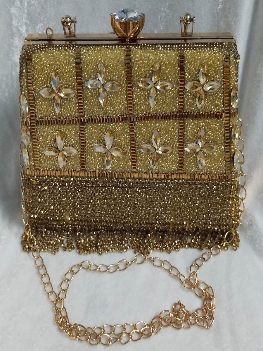 Gold beaded clutch with floral patterns and a chain strap on a light gray background