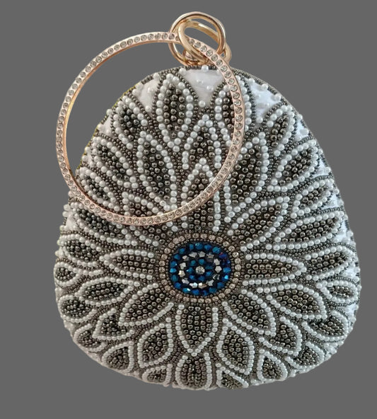 Decorative handbag with beadwork and a blue center on a gray background