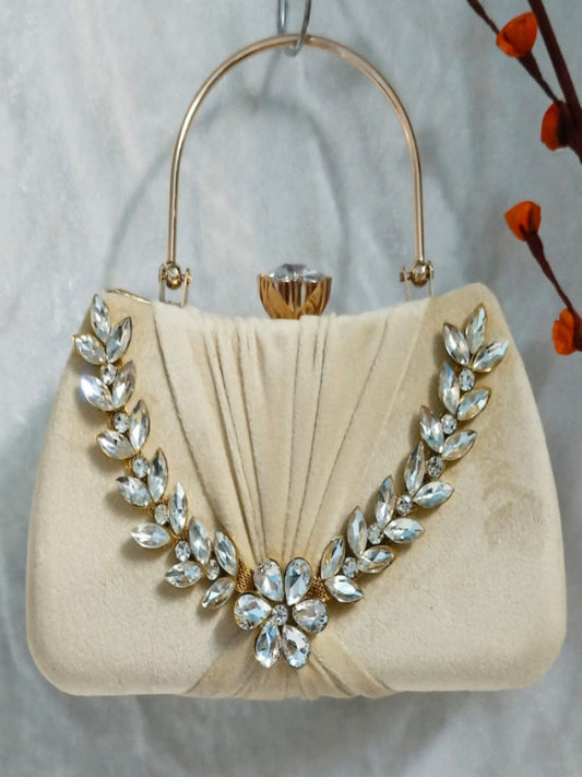 Beige handbag with decorative crystal embellishments on a neutral background