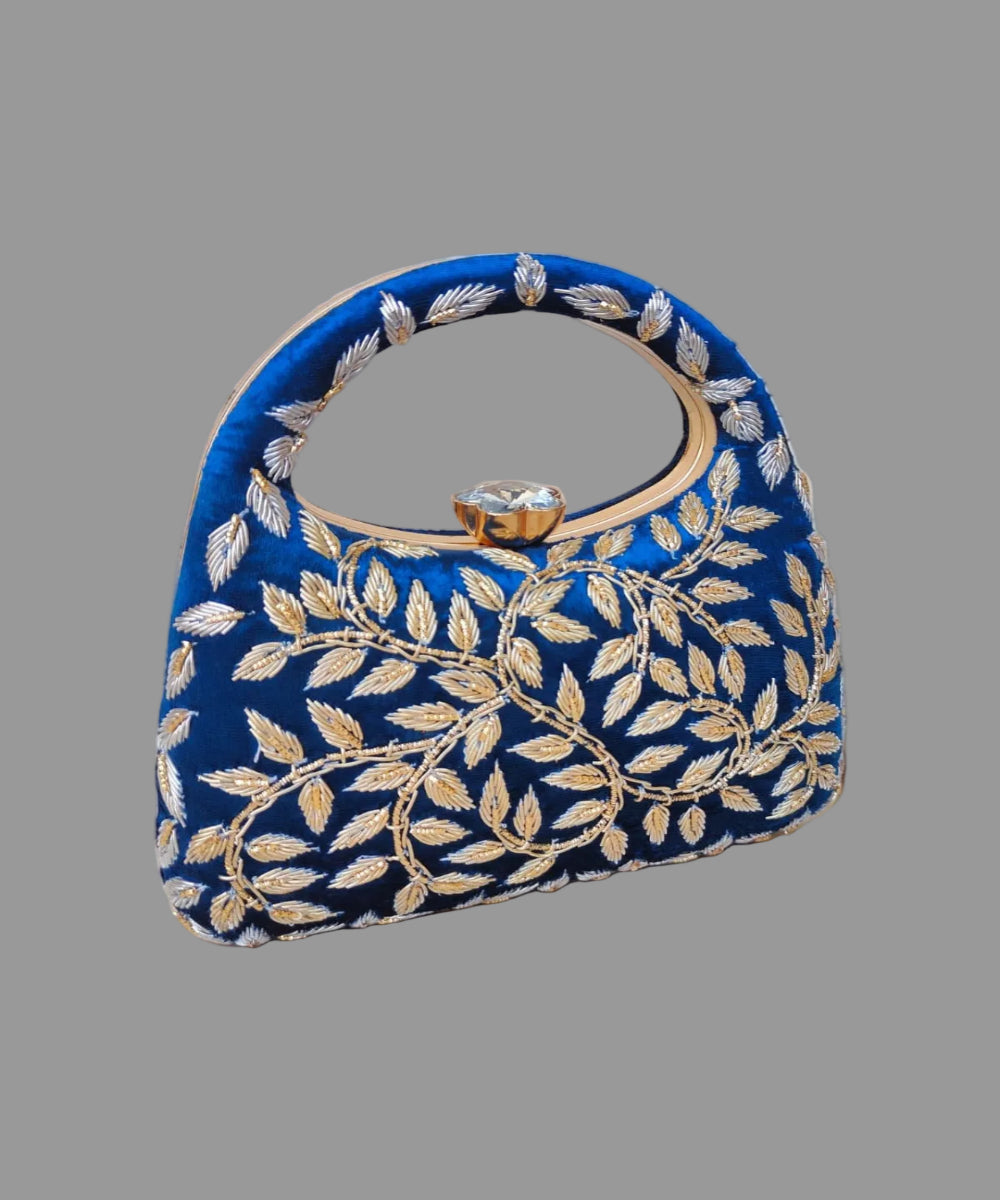 Blue handbag with gold leaf pattern on a wooden surface