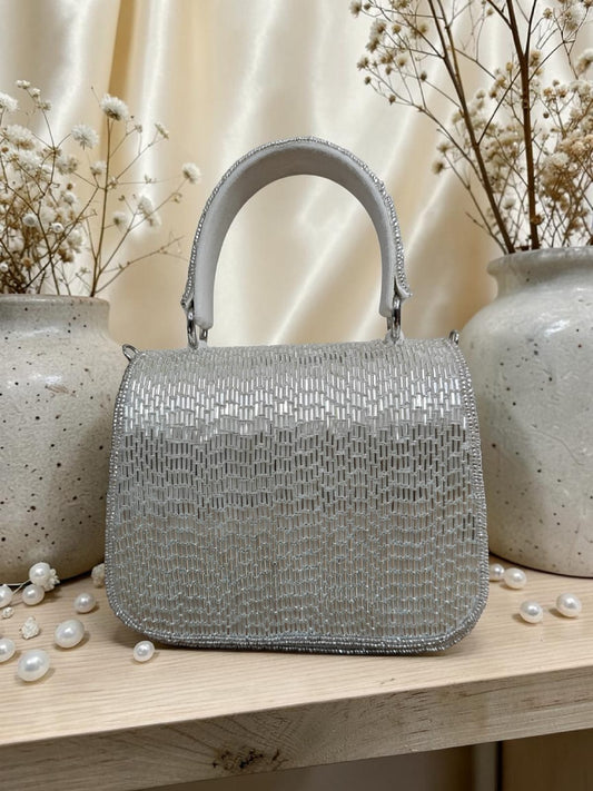 Silver beaded handbag on a wooden surface with decorative elements