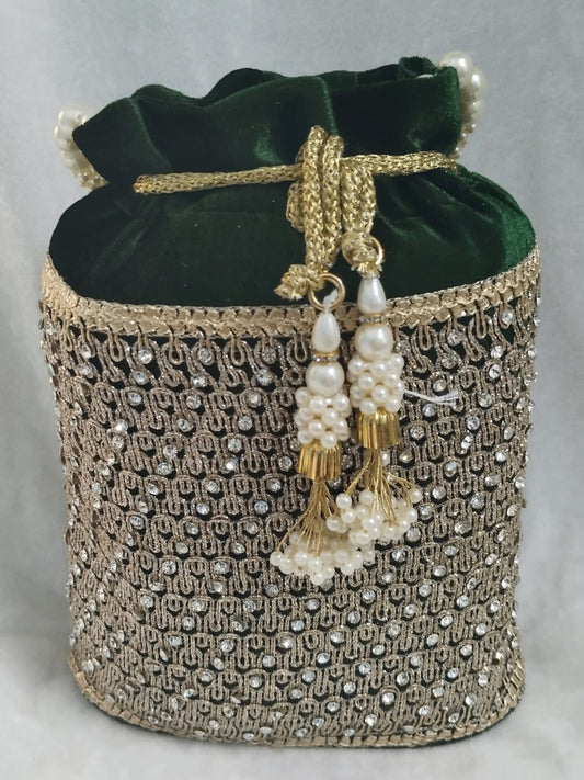 Decorative potli bag with green velvet top and gold embellishments on a light gray background