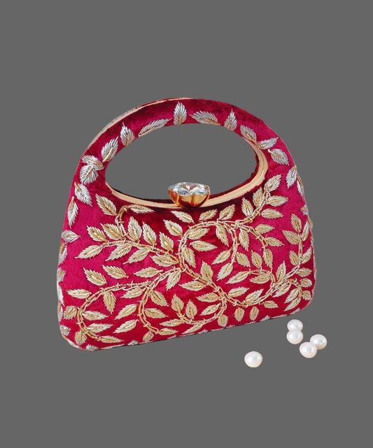 fuchsia handbag with gold leaf patterns on a wooden surface