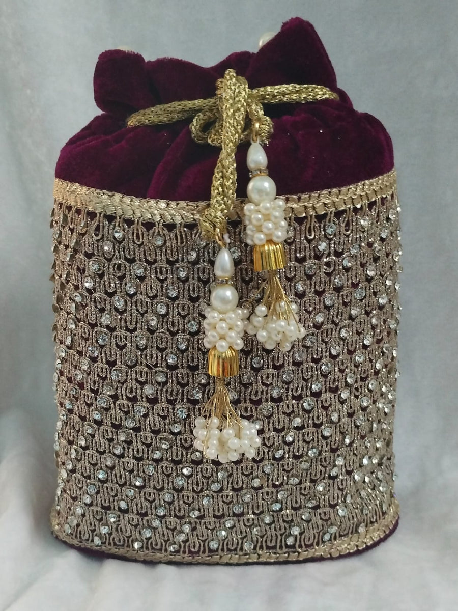 Decorative handbag with maroon velvet top and gold and pearl embellishments on a light gray background