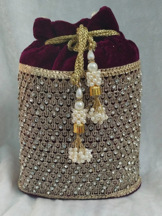 Decorative handbag with maroon velvet top and gold and pearl embellishments on a light gray background