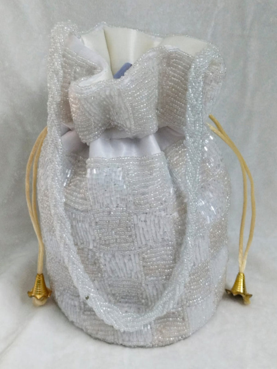 White beaded drawstring bag with gold tassels on a light gray background